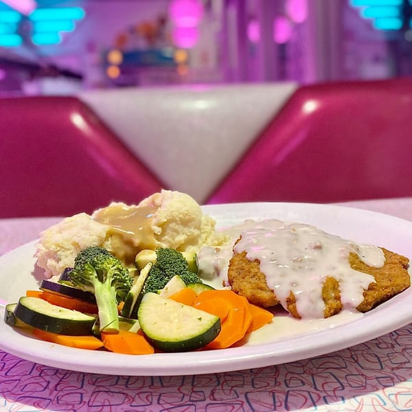 Beeps Diner's chicken fried steak with gravy, mashed potatoes, and mixed vegetables on a white plate.